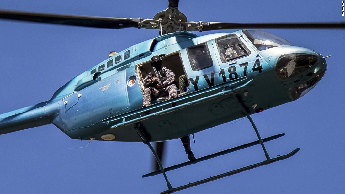 Members of the Venezuelan armed forces fly over Valencia in a helicopter while citizens demonstrate in support of a group that staged a paramilitary uprising at the Paramacay military base on August 6.