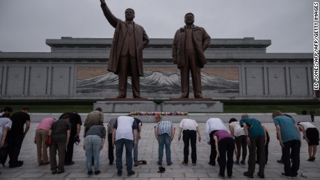 A group of tourists bow before statues of late North Korean leaders Kim Il Sung and Kim Jong Il , in Pyongyang on July 23, 2017.
