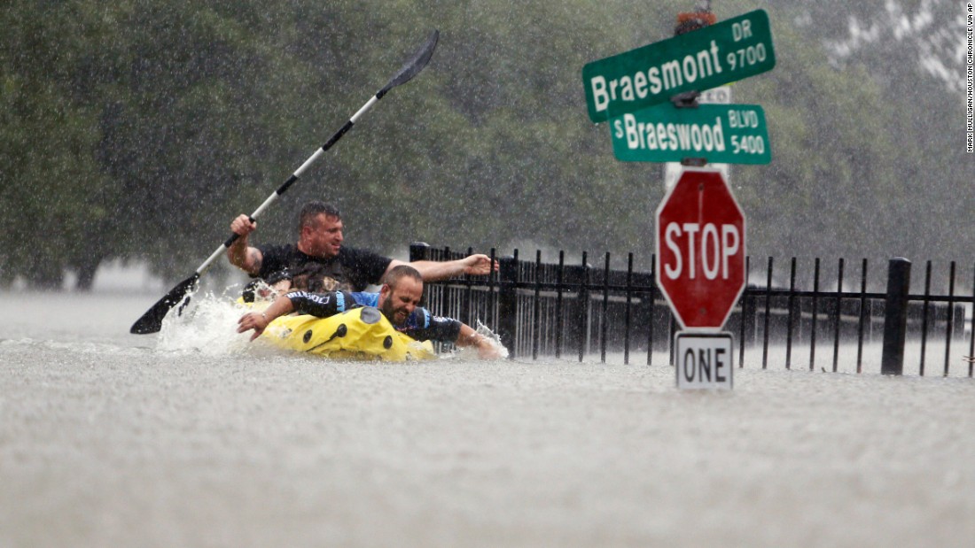 Two men try to beat the current that was pushing them down an overflowing Brays Bayou in Houston on August 27.