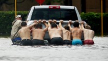 People push a stalled pickup through a flooded street in Houston.