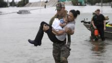 Houston police officer Daryl Hudeck carries Catherine Pham and her 13-month-old son, Aiden, after rescuing them from floodwaters.