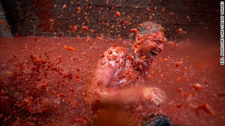 A reveller is pelted with tomato pulp during the annual "tomatina" festivities in the village of Bunol, near Valencia on August 31, 2016.  
Today at the annual Tomatina fiesta 160 tonnes of ripe tomatoes were offloaded from trucks into a crowd of 22,000 half-naked revellers who packed the streets of Bunol for an hour-long battle.



 / AFP / BIEL ALINO        (Photo credit should read BIEL ALINO/AFP/Getty Images)