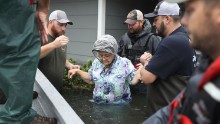 Volunteer rescue workers help a woman from her flooded home in Port Arthur, Texas.