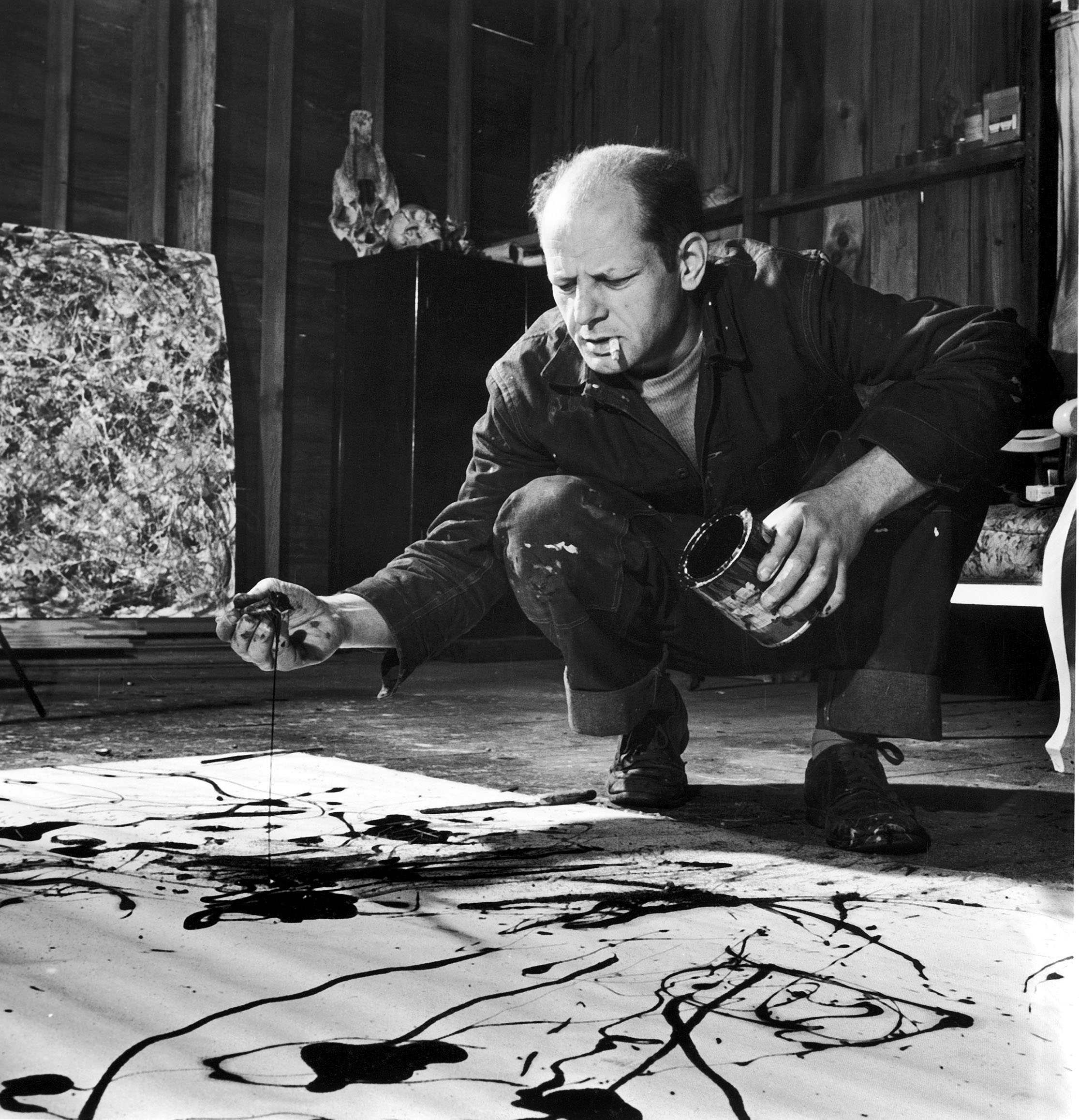 Jackson Pollock, cigarette in mouth, drops paint onto canvas. Getty Images