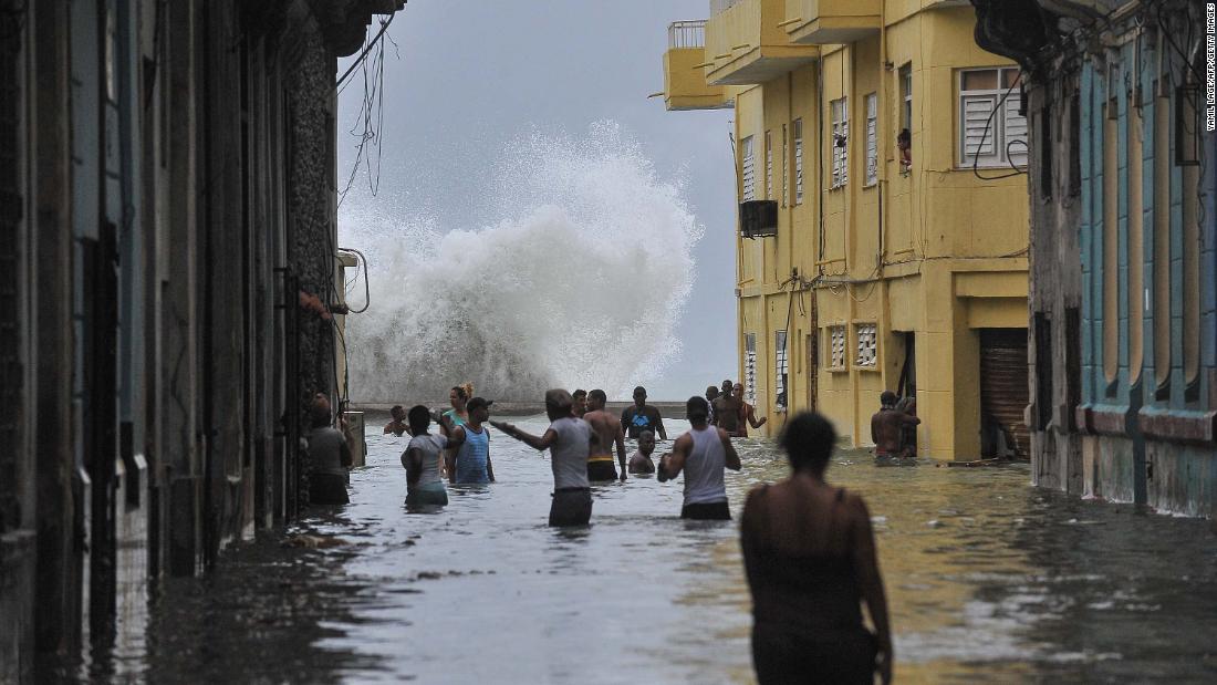 People wade through a flooded street as a wave crashes in Havana on Sunday, September 10.