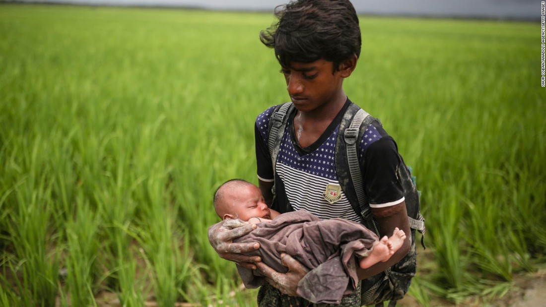 A Rohingya child holds a baby on September 12, as refugees wade through the Naf River in Bangladesh.