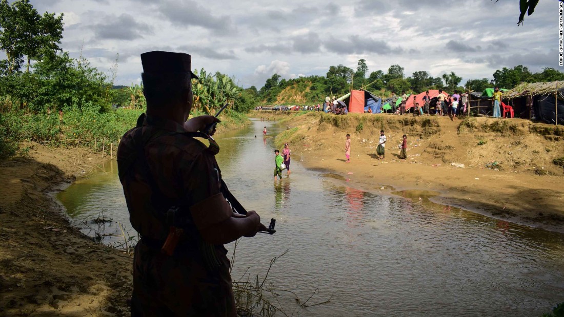 A Bangladeshi border guard orders Rohingya refugees to return to the Myanmar side of a small canal on August 29. Bangladesh has been struggling to cope with the influx of refugees.