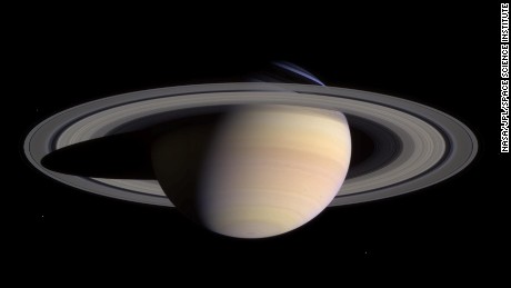 Saturn&#39;s pale colors and its rings come into view as Cassini approaches on May 7, 2004. This composite was made from images taken when Cassini was about 18 million miles (29 million kilometers) from Saturn. The small white dots are some of Saturn&#39;s moons.