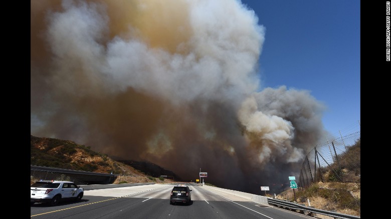Police cars block State Route 241 as smoke rises above Orange on October 9.