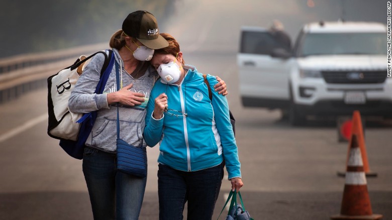 Colby Clark, left, comforts her mother, Bonnie Trexler, after law enforcement escorted them to Trexler&#39;s home in Napa, California, to retrieve medicine and personal items on Wednesday, October 11. Trexler was one of the lucky few in her neighborhood whose home was spared. Deadly wildfires have been tearing through the state, destroying homes and businesses and prompting evacuation orders.
