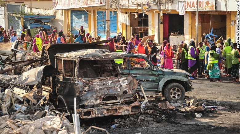People gather near burnt vehicles in the aftermath of the blast in Mogadishu. 