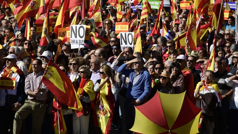 People hold signs reading &quot;No to the coup&quot; while waving Spanish flags during a demonstration urging unity in Madrid on Saturday.