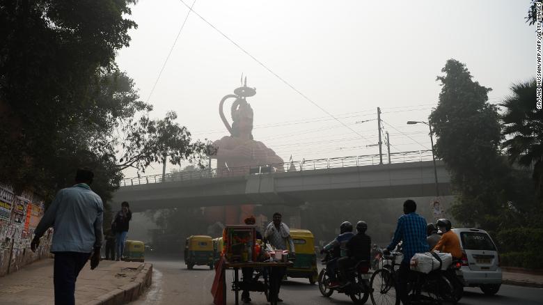 Indian commuters drive past the city&#39;s famous Hanuman Temple amid heavy smog. 