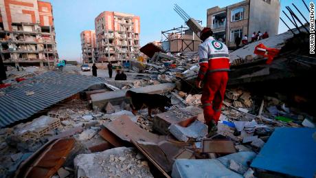In this photo provided by the Iranian Students News Agency, ISNA, a rescue worker searches debris for survivors with his sniffing dog after an earthquake at the city of Sarpol-e-Zahab in western Iran, Monday, Nov. 13, 2017. A powerful earthquake shook the Iran-Iraq border late Sunday, killing more than two hundreds people, Iranian state media said. (Pouria Pakizeh/ISNA via AP)