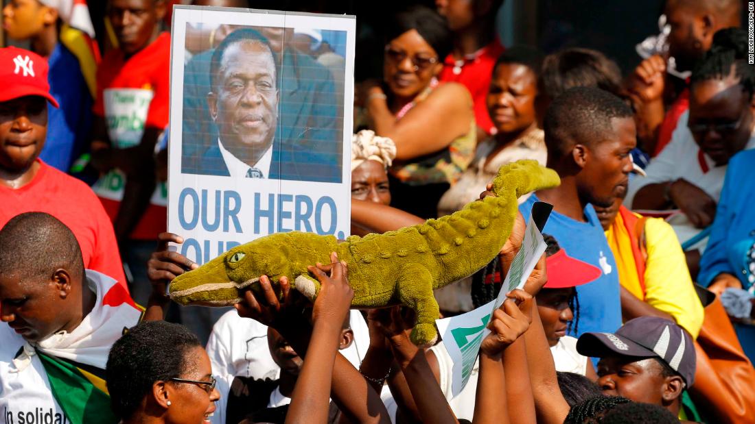 Supporters of Emmerson Mnangagwa hold up a toy to celebrate the man nicknamed &#39;The Crocodile&#39; as they waited at an airport for his arrival Wednesday. 