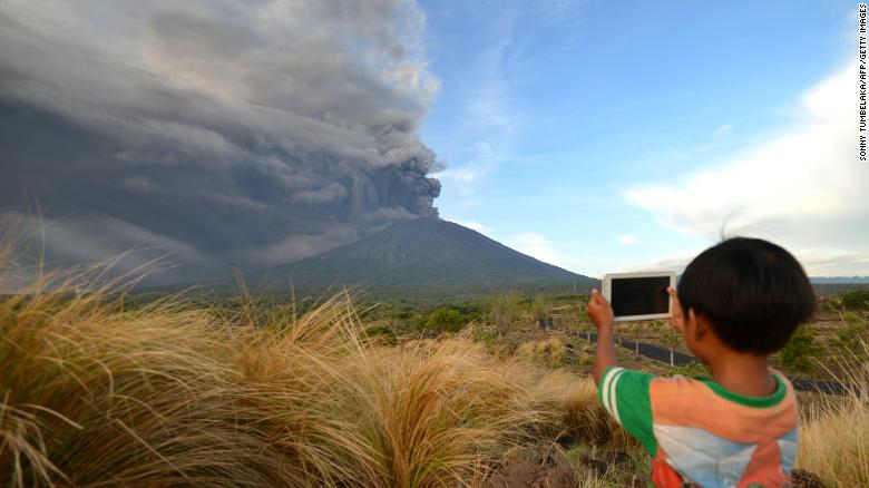 A boy takes pictures during Mount Agung's eruption on Indonesia's resort island of Bali on November 26,