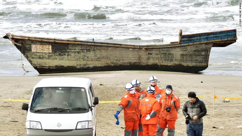 Japanese officials gather on Nov. 27, 2017, near a boat washed ashore in Oga, Akita Prefecture. Authorities found eight bodies in the unidentified wooden boat.