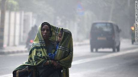 An Indian woman and her child walk amid heavy smog on a street in New Delhi on December 4, 2017.