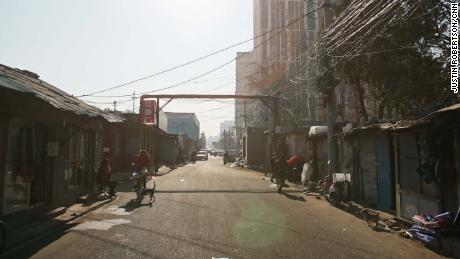 A street view of a once bustling market street after buildings on one side were demolished by authorities. Remaining stores prepare to shut down.