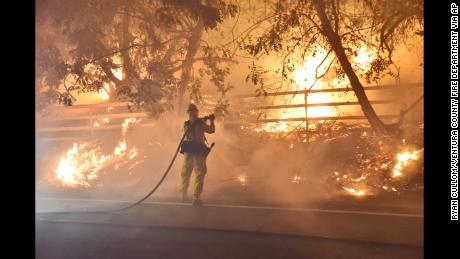 A firefighter works to put out flames early Tuesday in Santa Paula, California.