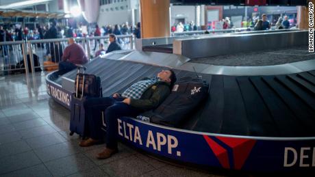 A traveler sleeps on a baggage carousel at Hartfield-Jackson Atlanta International Airport on Sunday.