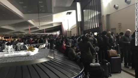 Stranded passengers congregate around baggage claim Sunday. 