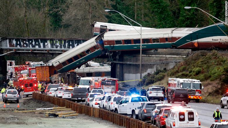 Cars from an Amtrak train lay spilled onto Interstate 5.