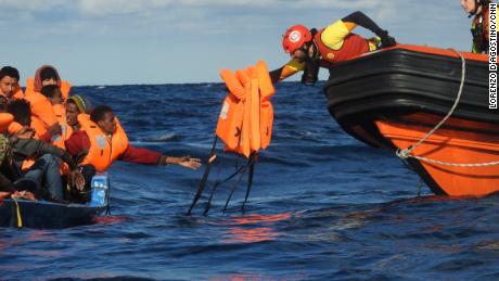 A rescuer hands out life jackets to migrants stranded in the Mediterranean.