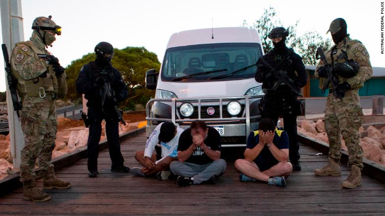 Three of the drug suspects, guarded by AFP officers, next to the van into which the drugs were loaded.