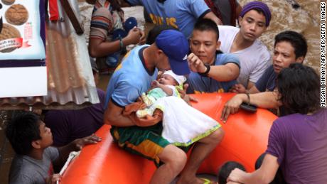 Police officers evacuate a baby Friday in Cagayan de Oro after Tropical Storm Tembin hit. 