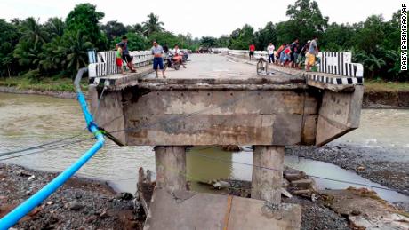 People gather on a bridge damaged by flooding from the storm Sunday in Zamboanga Del Sur in the southern Philippines. 