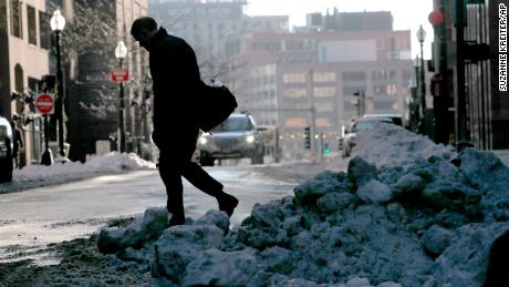 With snow on the ground, a person walks across the street on Tuesday.