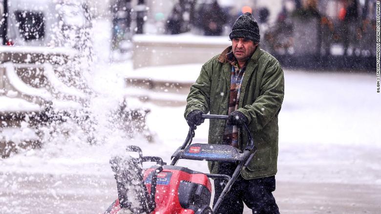 A man cleans a sidewalk with a snowplow during snowfall in Chicago on December 24.