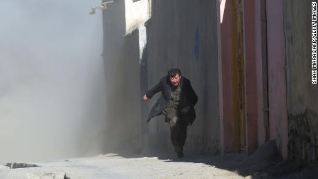 An Afghan man runs away as dust blows in the aftermath of the third blast at a Shiite cultural centre in Kabul on December 28, 2017.