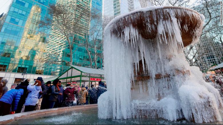 People pose for photographs in front of a frozen water fountain at Bryant Park in New York on Thursday. 