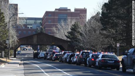 Officers from various police agencies line up in front of a Littleton hospital as they wait for a procession for a fallen deputy.