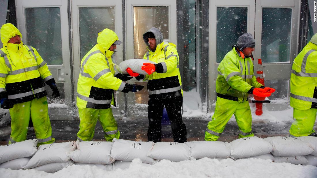 Workers on January 4 place sandbags in front of the Aquarium subway station to protect against flooding from Boston Harbor in Boston. 