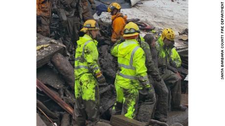 Firefighters lead a girl, 14, from the rubble where she'd been trapped for hours Tuesday in Montecito.