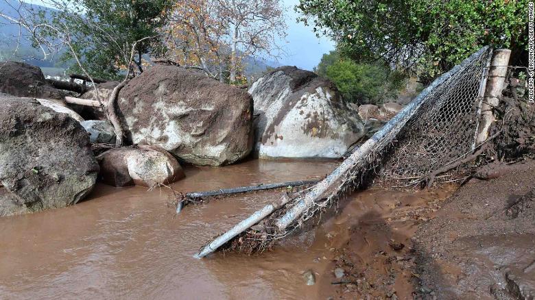 Mudslides pushed boulders near a broken fence in Carpinteria on Tuesday.