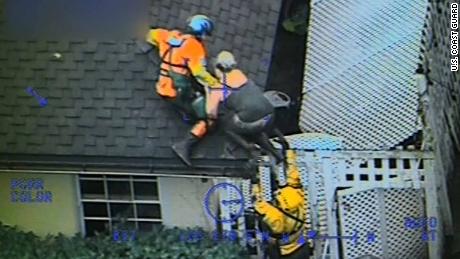 A Coast Guard helicopter crew pulls a person onto a roof after mud overtook a house in Carpinteria.