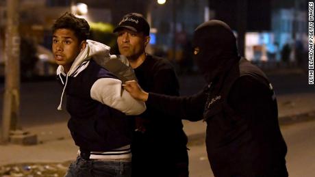 Tunisian security forces detain a protester on the outskirts of Tunis late on Wednesday.