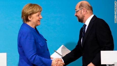 Merkel (L) shakes hands with Martin Schulz during a joint statement after talks on Friday.