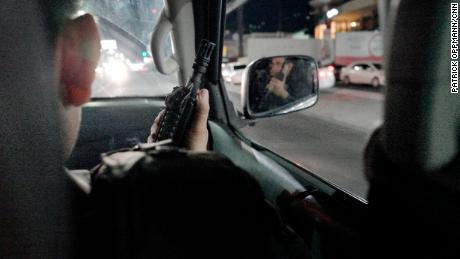 While on patrol, a member El Salvador's National Civil Police points his assault rifle out the car window. Police say gang members often possess more fire power than they do.