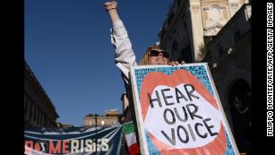 A woman lifts her fist while holding a banner during a Women&#39;s March demonstration in Rome on Saturday.