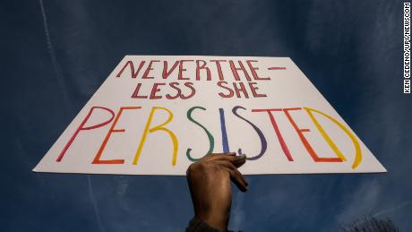 A woman holds a sign in front of the White House in Washington.