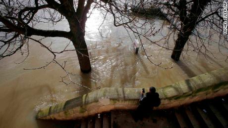 A man takes a photo of the Seine on Friday, days after the river burst its banks.