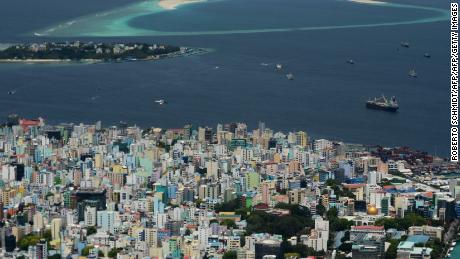 To go with MALDIVES-ENVIRONMENT-WASTE-TOURISM,FEATURE by ADAM PLOWRIGHT
In this photo taken on September 11, 2013, smoke billows from Thilafushi Island (top) not far from the densely populated capital of the Maldives, Male (below). Descending by plane into the Maldives offers a panoramic view of azure seas and coral-fringed islands, but as the tarmac nears billowing smoke in the middle distance reveals an environmental calamity. Thilafushi Island, a half-hour boat trip from the capital, is surrounded by the same crystal clear waters and white sand that have made the Indian Ocean archipelago a honeymoon destination for the rich and famous.       AFP PHOTO/ Roberto SCHMIDT        (Photo credit should read ROBERTO SCHMIDT/AFP/Getty Images)