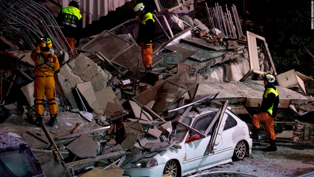 Members of the emergency services search for people in the debris of a collapsed building.