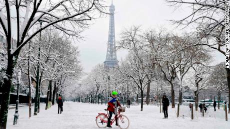 People walk through the snow covered alley of the Champ de Mars following heavy snowfall in Paris, on February 7, 2018 near the Eiffel tower.
Exceptionally heavy snowfall brought public transport in Paris and surrounding regions to a near halt on February 7, spelling misery for commuters after hundreds were forced to abandon their cars to sleep in emergency shelters overnight.  / AFP PHOTO / Thomas SAMSON        (Photo credit should read THOMAS SAMSON/AFP/Getty Images)