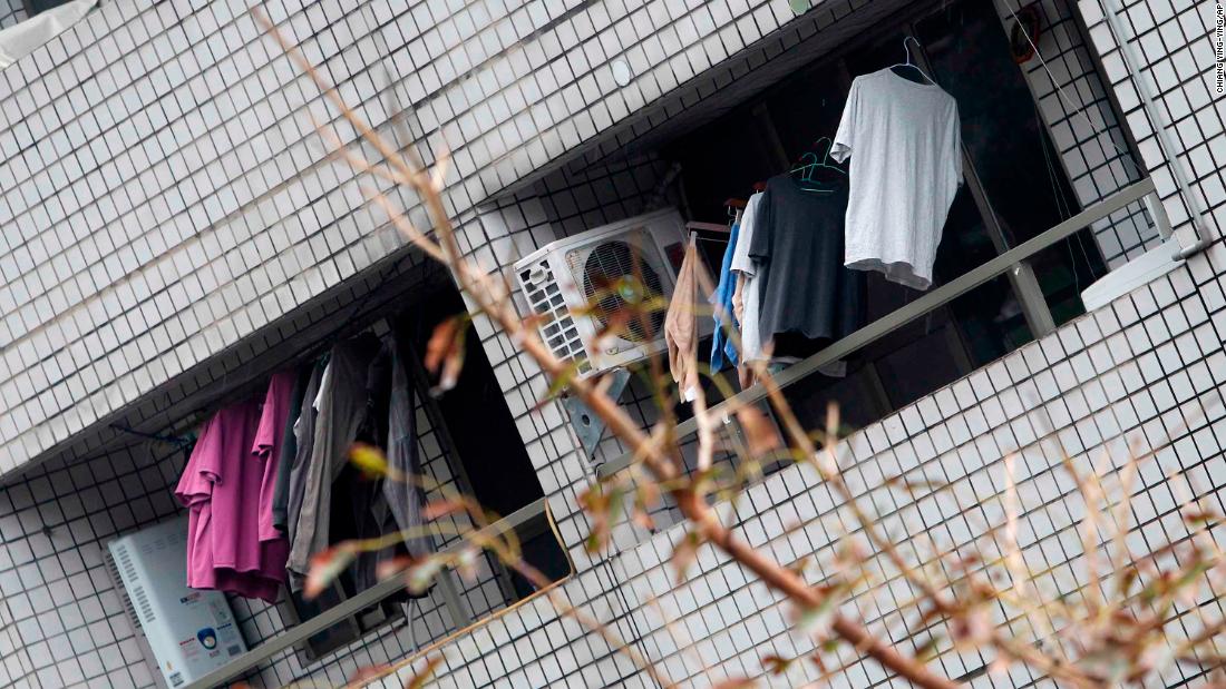 Clothes hang on the balcony of a leaning apartment building.